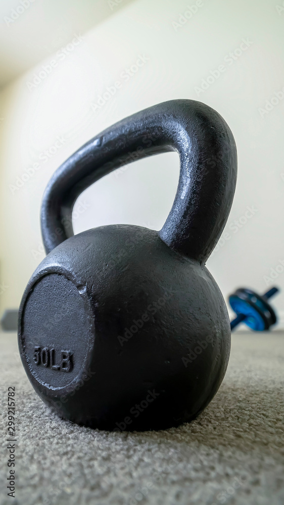 Vertical Close up of black kettlebell inside a gym room with carpet floor and white wall Vertical Close up of black kettlebell inside a gym room with carpet floor and white wall