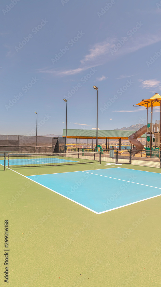 Vertical Two empty outdoor pickleball courts on sunny day
