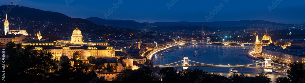 Panorama of Budapest along the Danube River featuring the Chain Bridge and Hungarian Parliament Building at blue hour. 