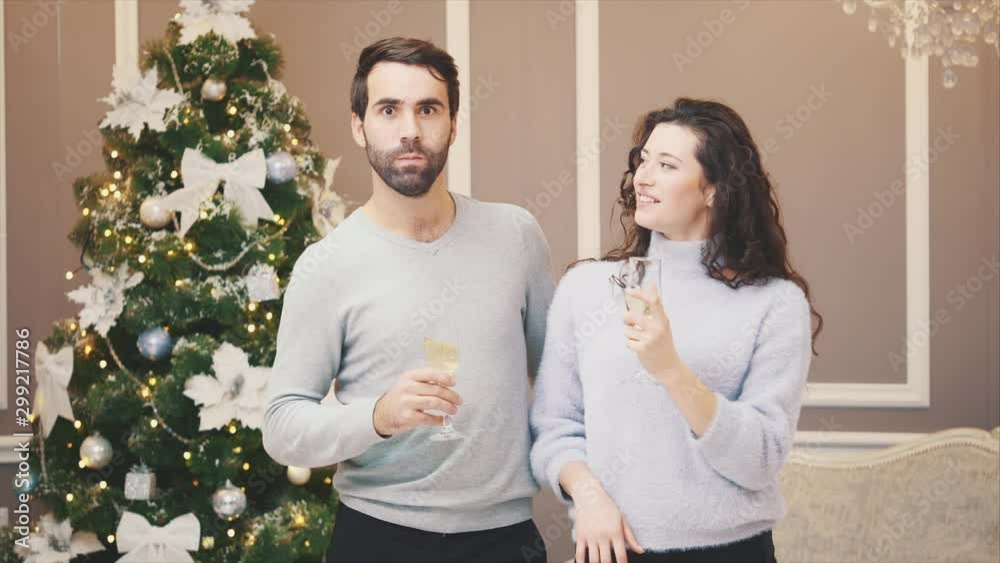 Toasting with champagne glasses against holiday lights and christmas tree.