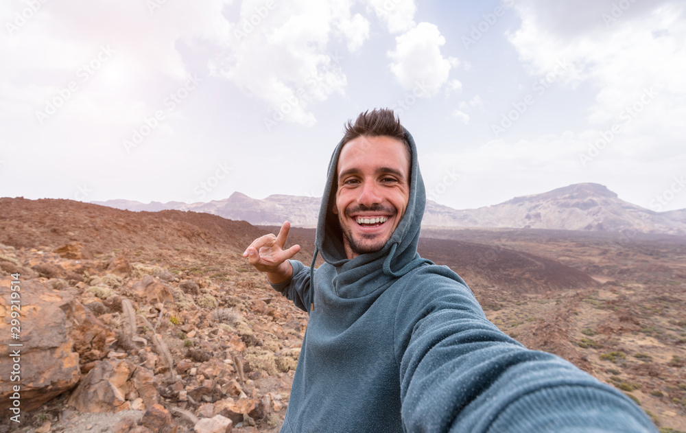 Handsome hiker taking a selfie hiking a mountain using his smartphone