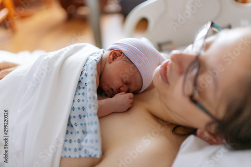 newborn baby in hospital after just being born, mother holding him and breastfeeding in hospital bed