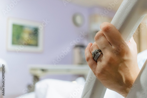 mother in hospital bed pregnant and in labor, holding on to bed rail in pain, wedding rings showing