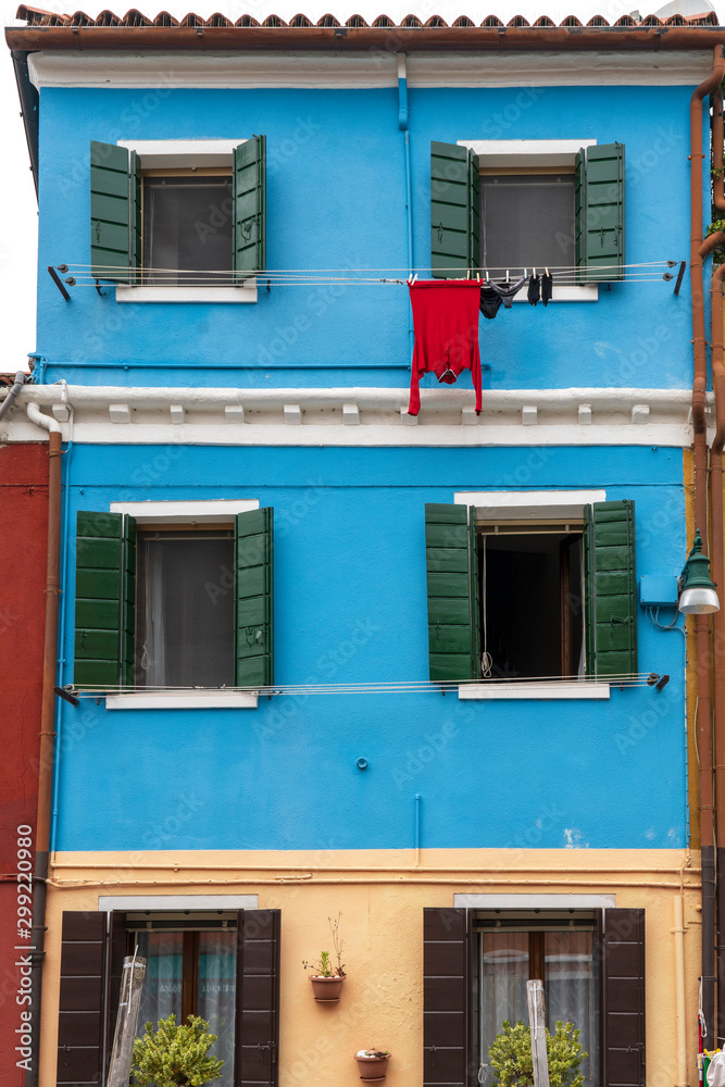 The facade of a blue house with a laundry rack outside in Burano, Venice, Italy: May 21, 2019. Burano is near Venice, and is famous for its canals and charming. - Immagine
