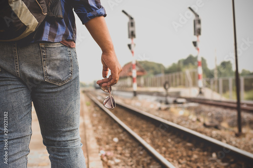 The male tourists are standing at the railway station, tourism and transportation.