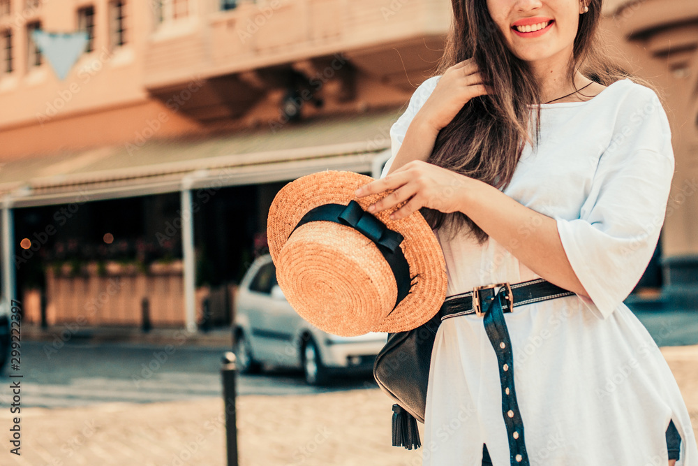 Young stylish woman walking on the street, travel with backpack, straw hat, wearing trendy outfit.