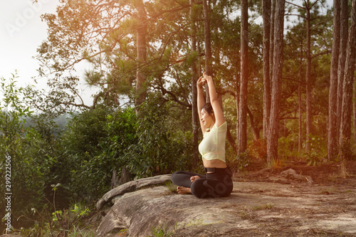 Young beautiful Asian woman practices yoga and meditates outdoor in the forest. Female doing yoga and meditate to relax and release stress. Weight Loss. Health care and lifestyle.