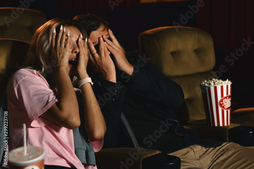 caucasian couple wathing horror movie and putting hands cover face when having scary scene photo