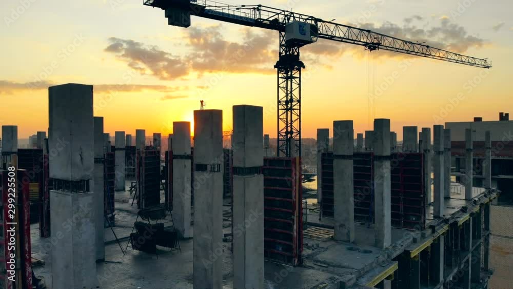 High crane works on building site with a house.