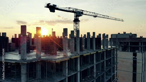 Building and crane on sunset background.