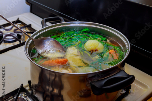 Preparing homemade chicken soup with vegetables in metal pan