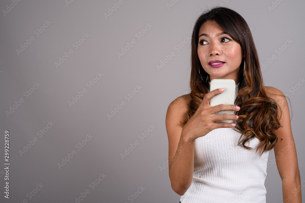 Portrait of Asian woman with wavy hair using phone