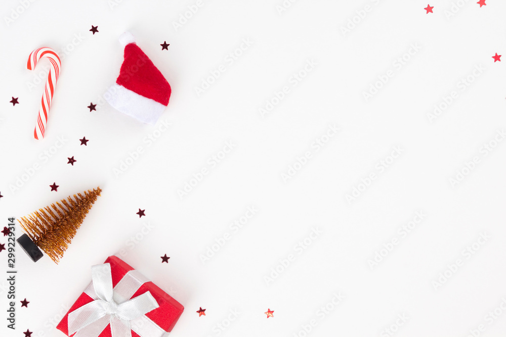 Red Christmas gift, Santa's hat, candy cane, golden fir on white background. Congratulation, Happy New Year concept. Top view, flat lay, copy space - obrazy, fototapety, plakaty 