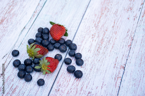 Blueberries and straweberries on a wooden table background. Summer healthy lifestyle concept