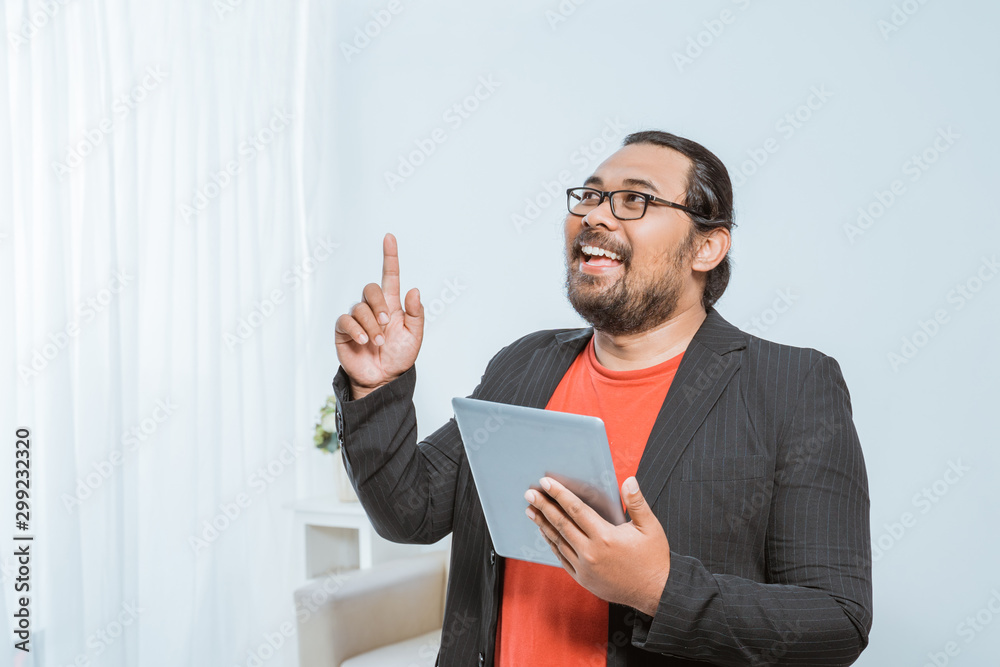 portrait of happy entrepreneur pointing his finger up while holding tablet pc portrait of happy entrepreneur pointing his finger up while holding tablet pc