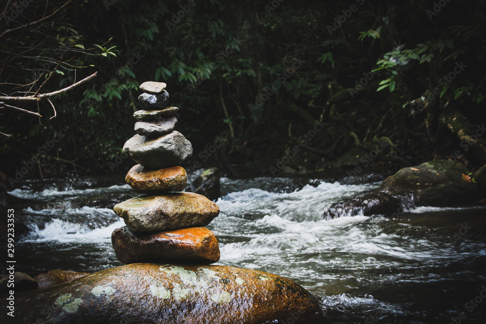 Balanced stone pyramide on shore of water fall of mountain lake. Blue mountains in water level mirror. Poor lighting conditions. Balanced stone pyramide on shore of water fall of mountain lake. Blue mountains in water level mirror. Poor lighting conditions.