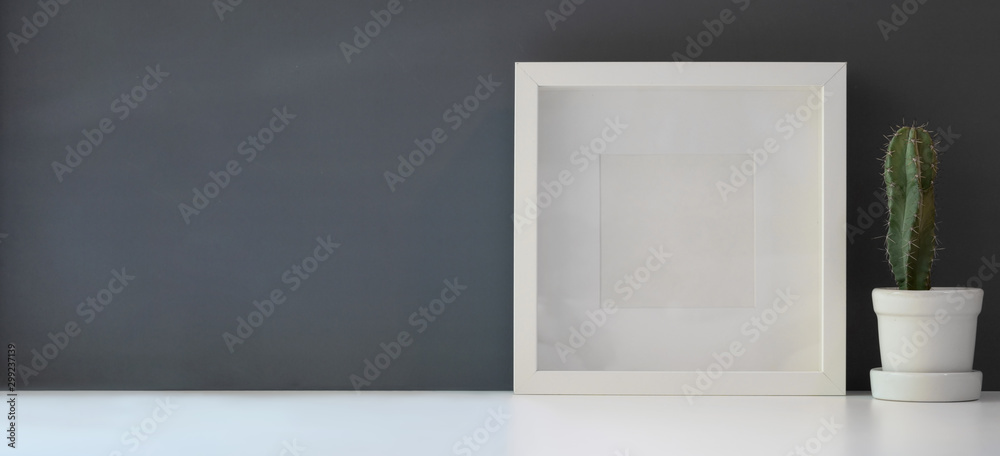 Mock up frame with cactus in pot in modern workspace on white table and dark grey wall Mock up frame with cactus in pot in modern workspace on white table and dark grey wall