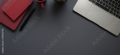 Top view of dark modern workplace with laptop computer, office supplies and red notebook with copy space