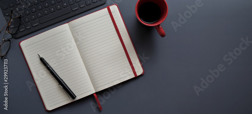 Принти на полотні Top view of dark modern workplace with open notebook and red coffee cup
