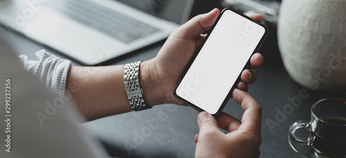 Close-up view of businessman holding blank screen smartphone in his modern office room photo