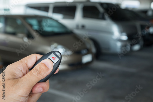 Hand holding car key remote at car park
