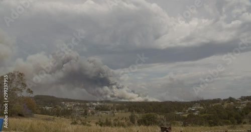 The heavy, black smoke from out of control fires, during a 36-degree day, with severe fire danger rating, at Darawank along Failford Road on 26th of October 2019, New South Wales, Australia photo