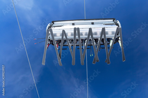 Winter sports concept: People with ski equipment on a ski lift upside down in winter sunny day at alpine ski resort. Copy space. photo