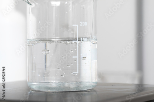 Obraz na plátne Beaker with water, clear liquid in lab mixer close up