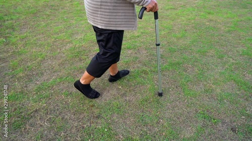 slow-moiton of senior woman legs walking with walking stick in the grass field photo