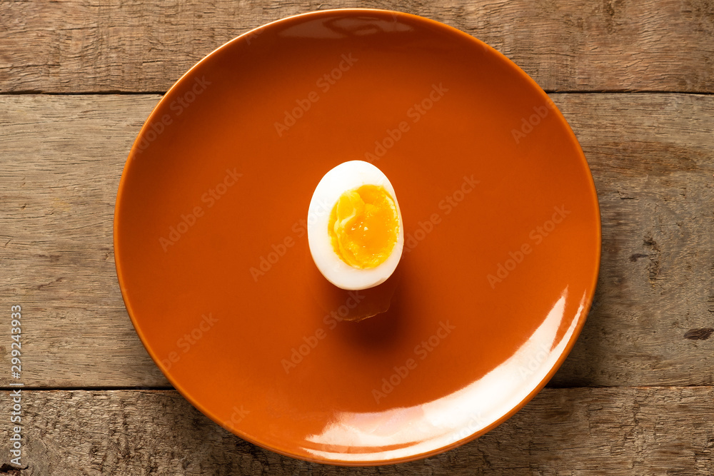 Medium-boiled eggs in a brown ceramic dish on a wooden table. Top view. Health concept. Medium-boiled eggs in a brown ceramic dish on a wooden table. Top view. Health concept.