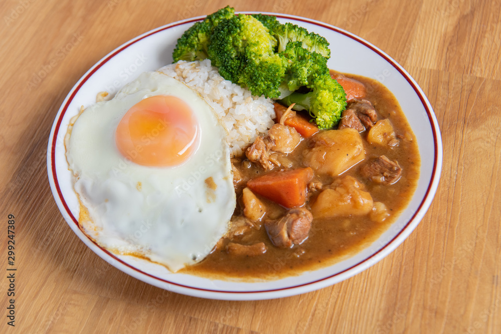 Chicken curry Rice on wooden background ( Poached egg, Potato, enoki mushroom, onion, broccoli, Japanese style,) Chicken curry Rice on wooden background ( Poached egg, Potato, enoki mushroom, onion, broccoli, Japanese style,)