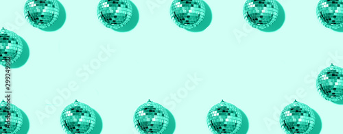 Creative Christmas pattern. Frame with shiny gold disco balls over mint background. Flat lay, top view. New year baubles, star sparkles. Trendy green and turquoise color. Cristmas greeting card