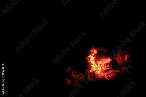 Coals on a black background. Copy space Smoldering embers. The silhouette of Satan. Halloween fantasy mesteria concept.