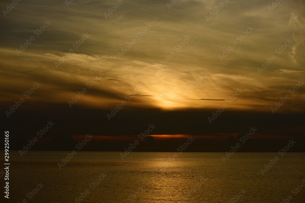 Obraz premium The view of the golden sky, the sea and a small fishing boat in the early morning, the sun is rising. 