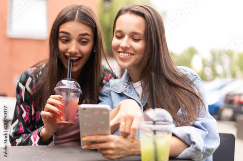 Young girls friends watch something in smartphone.