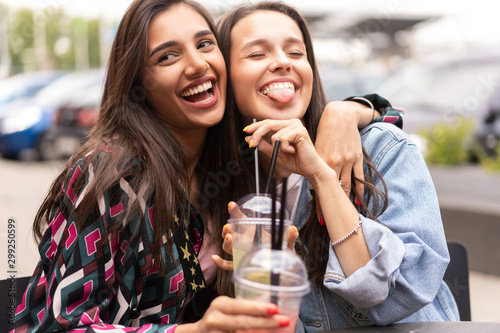 Hipster girlfriends drink cocktail in urban city background