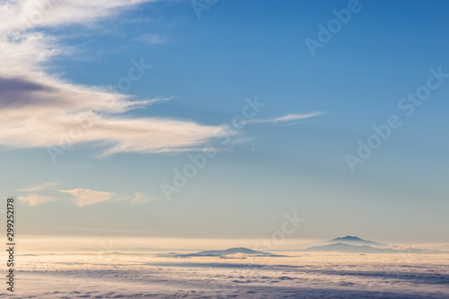 Distant mountains above a sea of fog like islands at sunset