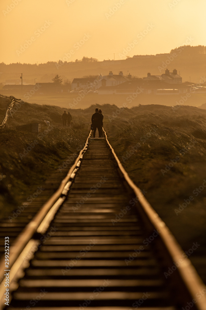 Couple walks down the rail track in  a golden hour