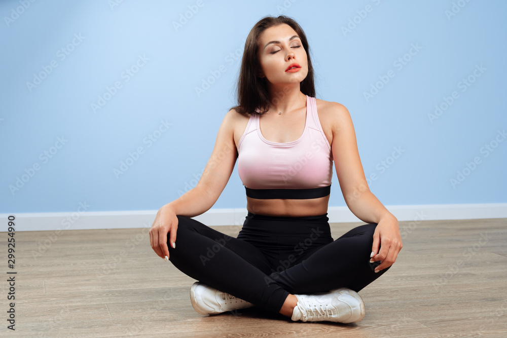 Fit woman in sportswear sitting on the floor in a gym
