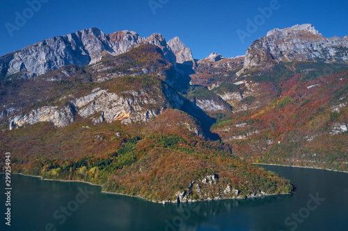 Aerial view of Lake Molveno, north of Italy. In the background rocky alps, blue sky. Autumn season. Multi-colored palette of colors
