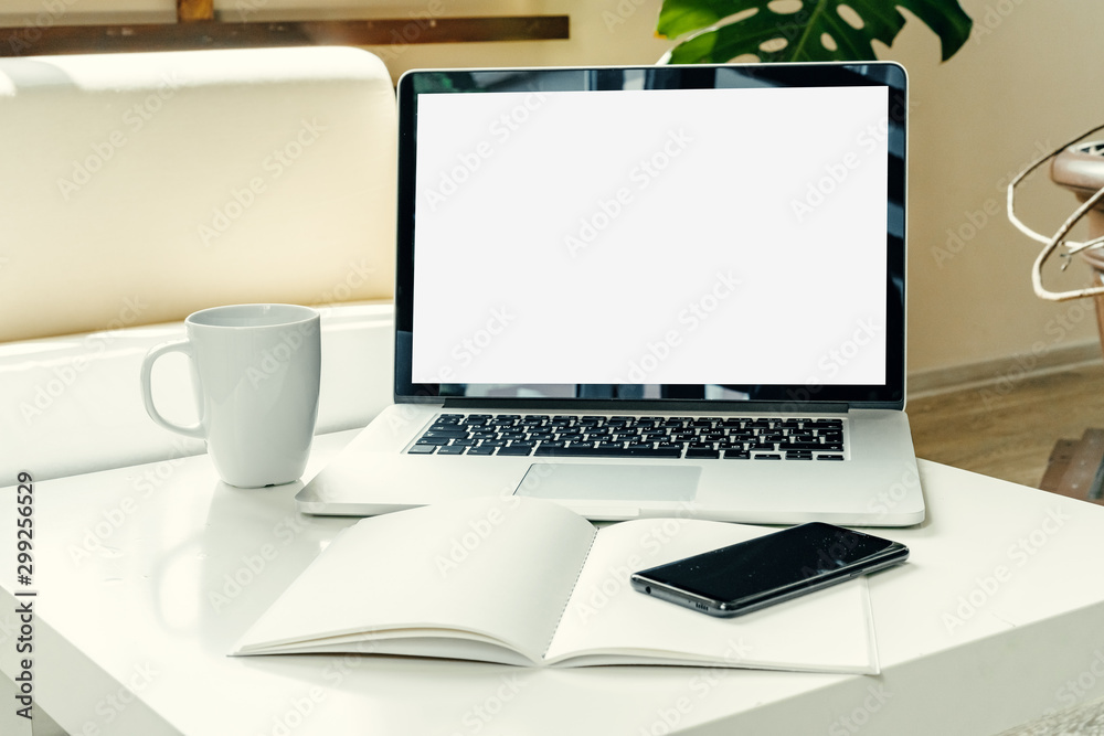 Open laptop on table near sofa, home interior. Freelancer workplace concept Open laptop on table near sofa, home interior. Freelancer workplace concept