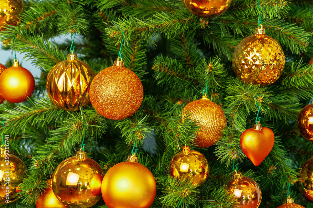 Christmas tree with golden baubles close up on blue background