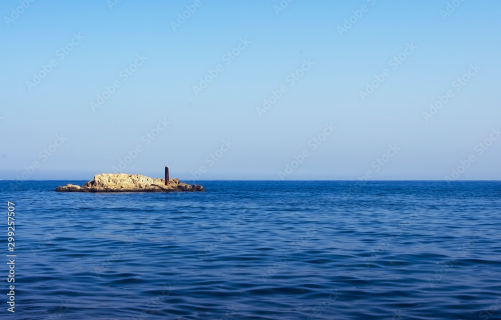 Rocky outcrop in ocean with blue sky