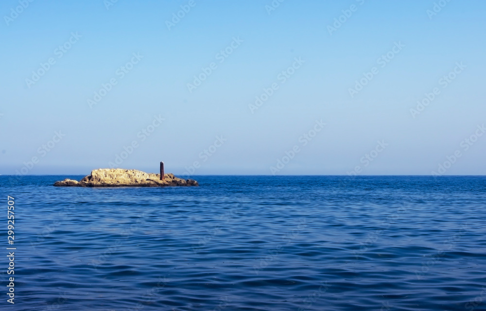 Rocky outcrop in ocean with blue sky Rocky outcrop in ocean with blue sky