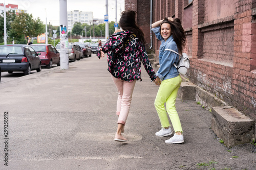 Outdoors fashion portrait young pretty best girls friends in friendly hug. Walking at the city. © opolja