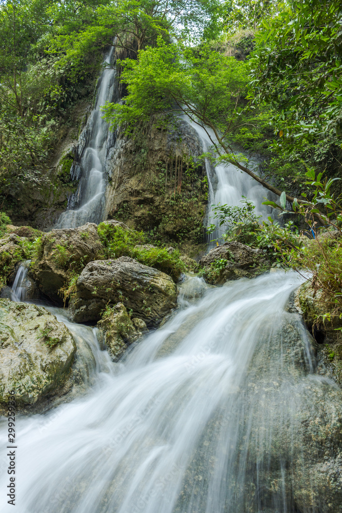 Beautiful waterfall with green leaves in long exposure mode, Indonesia Beautiful waterfall with green leaves in long exposure mode, Indonesia