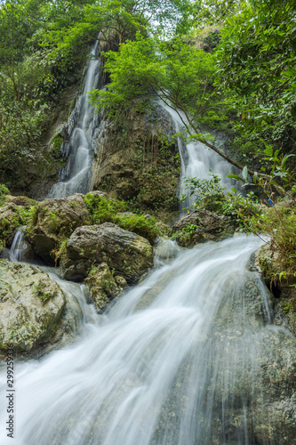 Beautiful waterfall with green leaves in long exposure mode, Indonesia