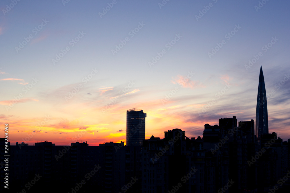 Dark silhouettes of urban buildings, houses and skyscrapers on background of colorful sunset with cirrus clouds, St. Petersburg, Russia