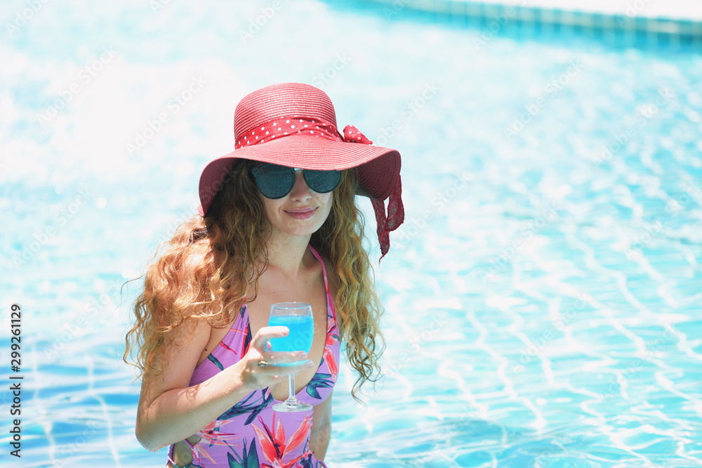 The woman in a swimsuit wears a hat and glasses at the poolside The woman in a swimsuit wears a hat and glasses at the poolside