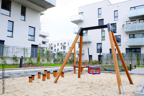 Playground with a children swing in cozy courtyard of modern residential district.